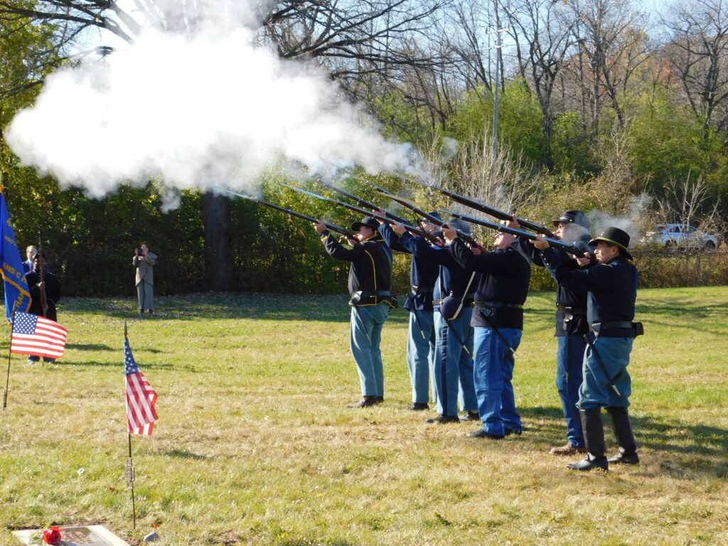 Men in Civil War uniforms fire rifles into the air.